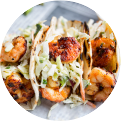 Grilled shrimp tacos with cabbage slaw on soft tortillas, arranged in a row